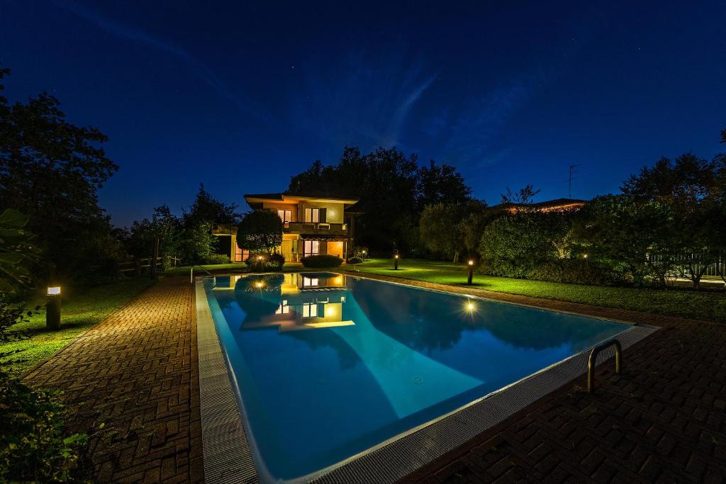 une piscine devant une maison la nuit dans l'établissement Villa dei Salici con Piscina by Wonderful Italy, à Soiano del Lago