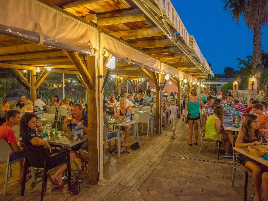 un groupe de personnes assises à des tables dans un restaurant dans l'établissement Camping Les Palmiers, à Hyères