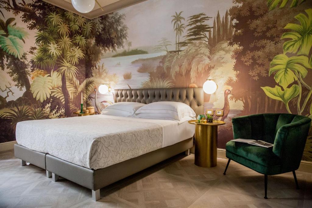 une chambre avec un grand lit et une chaise verte dans l'établissement Hotel Savoia, à Alassio 108 autres photos