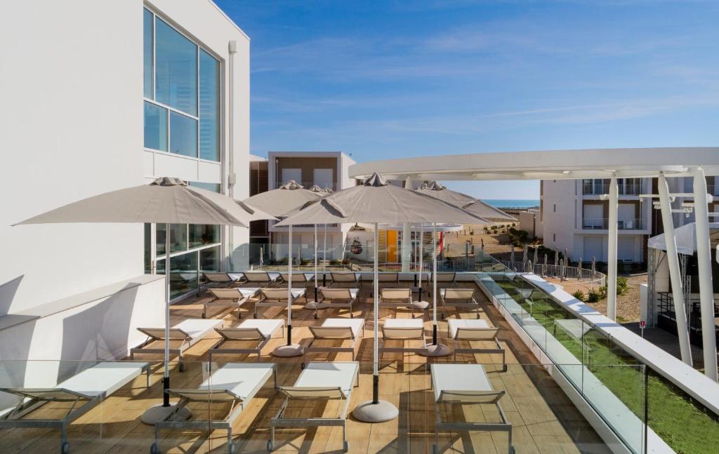 un patio extérieur avec tables, chaises et parasols dans l'établissement Hapimag Apartments Cavallino, à Cavallino-Treporti