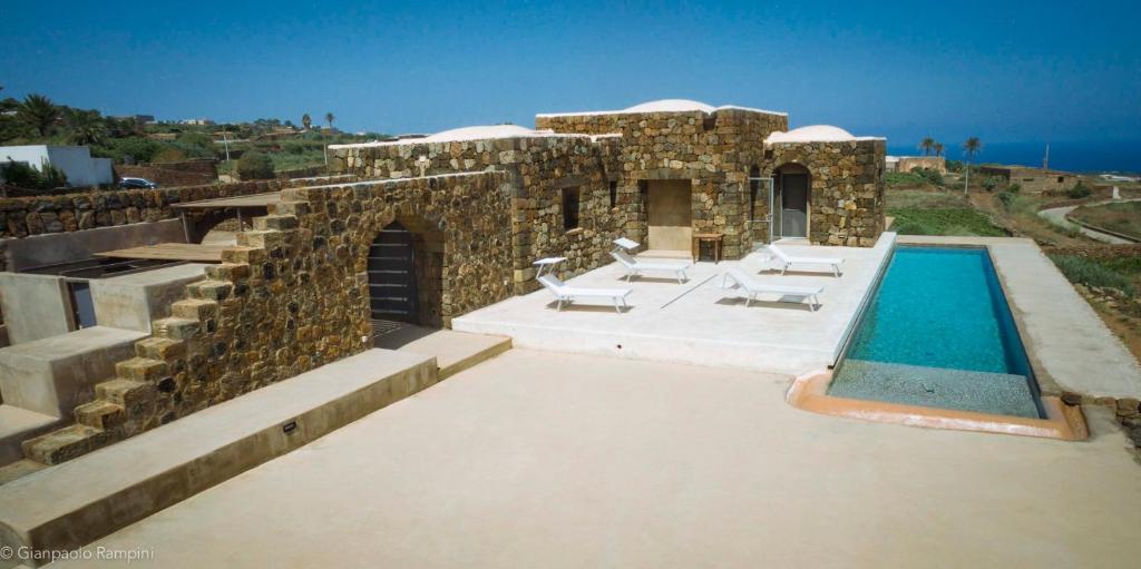 une maison en pierre avec une piscine et quelques chaises dans l'établissement Dammuso Kaddiuggia Antica Pantelleria, à Pantelleria 9 autres photos