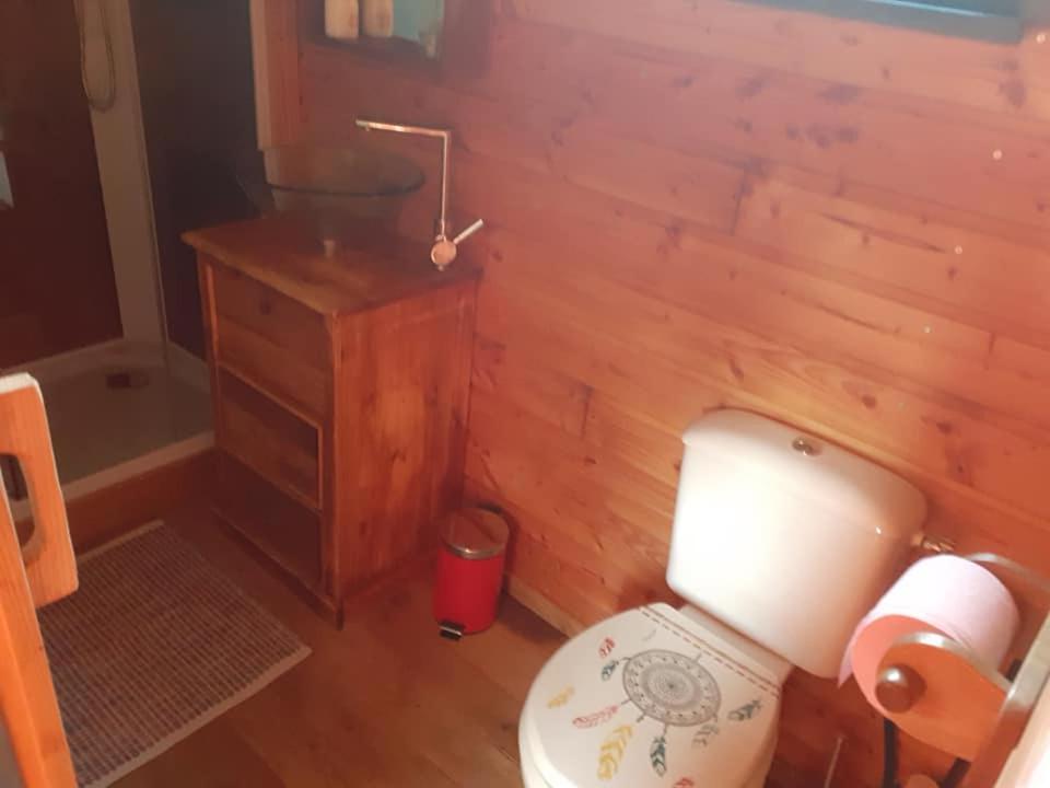 La salle de bains est pourvue de toilettes et d'un mur en bois. dans l'établissement La Roulotte de la Clef des Champs, à Buzancy