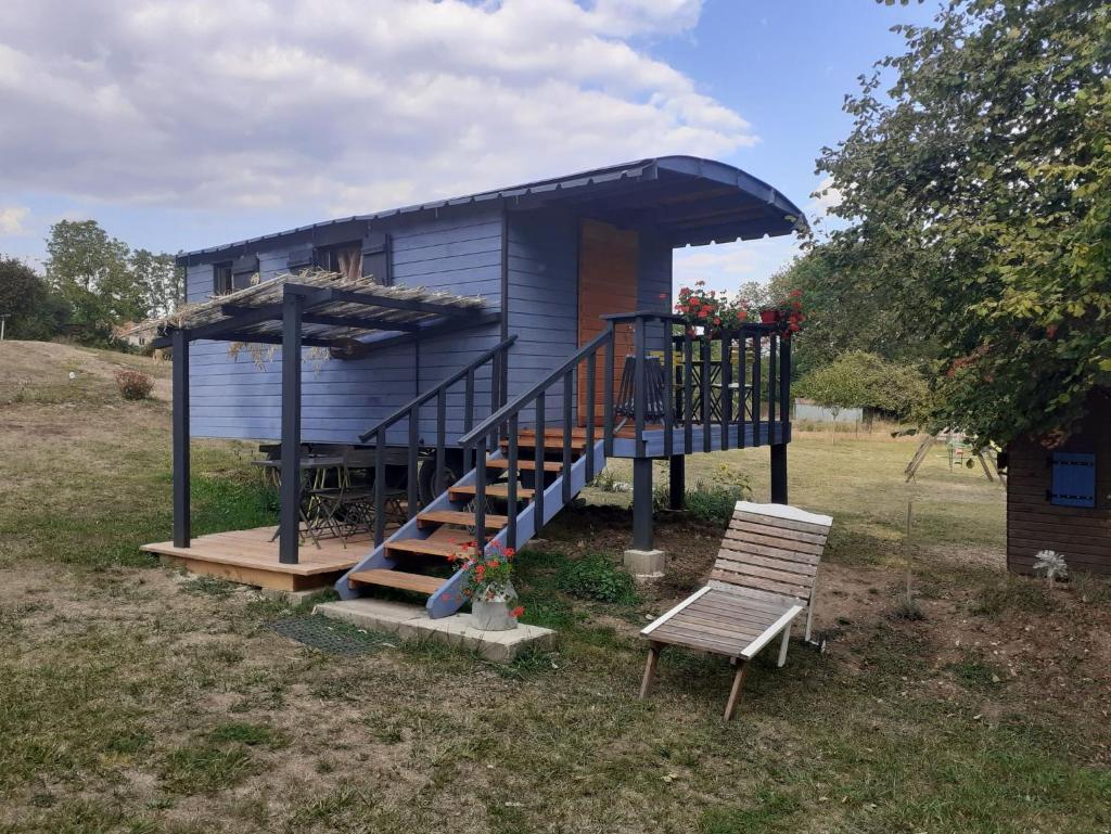 une maison bleue avec un escalier et une chaise dans l'établissement La Roulotte de la Clef des Champs, à Buzancy
