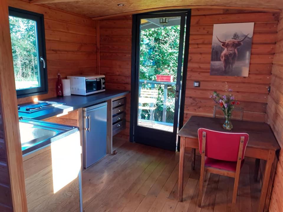 une cuisine avec une table et une chaise rouge dans l'établissement La Roulotte de la Clef des Champs, à Buzancy