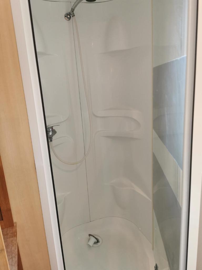 La salle de bains est pourvue d'une douche en verre et de toilettes. dans l'établissement Assist' Mobil Home 276 - Mobil home 3 chambres au calme, à Onzain 8 autres photos