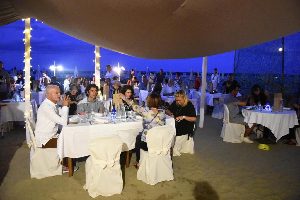 un groupe de personnes assises autour d'une table dans une tente dans l'établissement Hotel Souvenir, à Lido di Savio