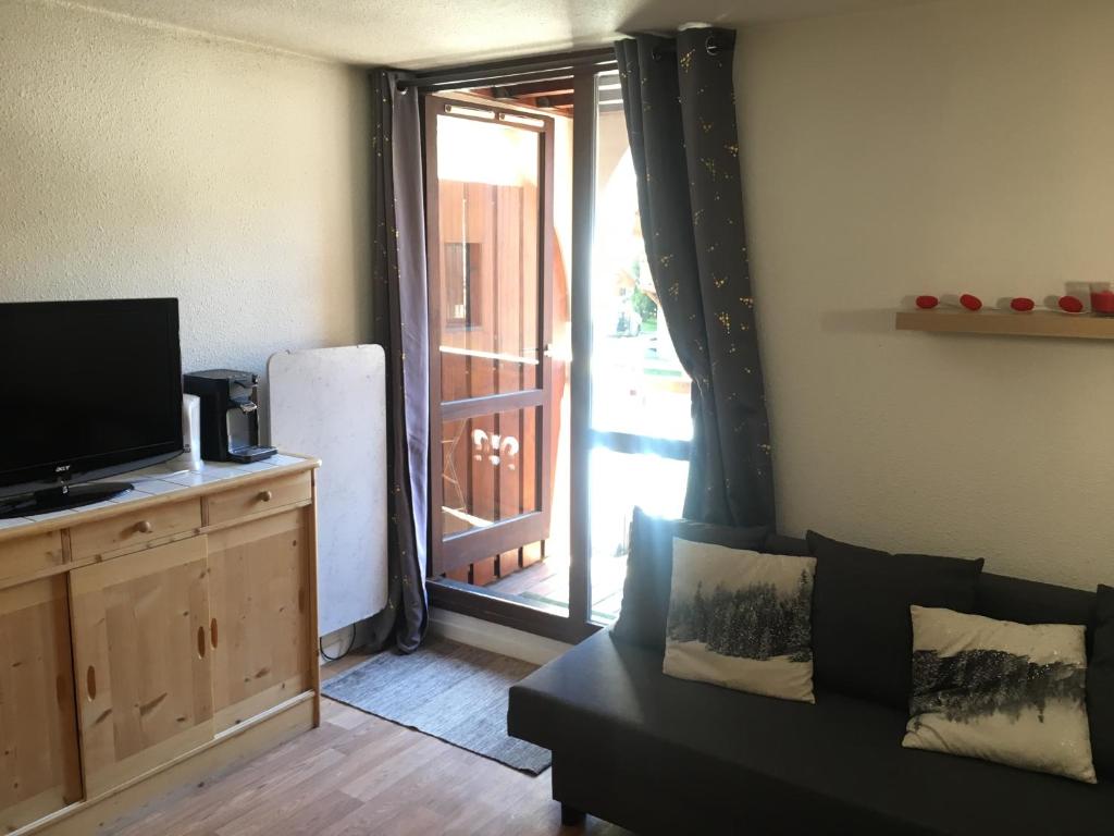 un salon avec un canapé et une porte coulissante en verre dans l'établissement Cosy central Studio with a view, balcony 20m2 4ppl, à Vénosc