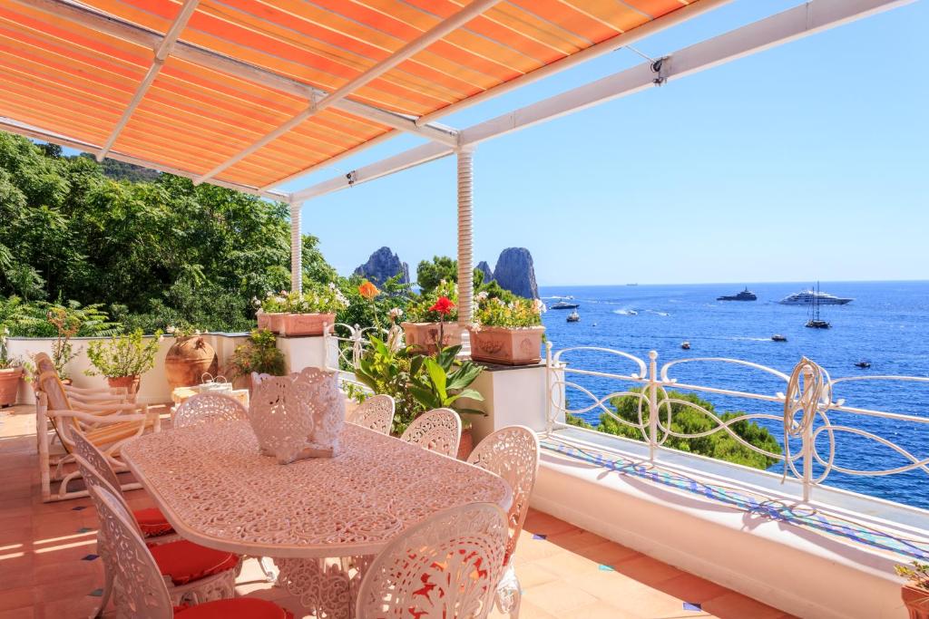 une table et des chaises sur un balcon avec vue sur l'océan dans l'établissement Villa Teste di Moro, à Capri