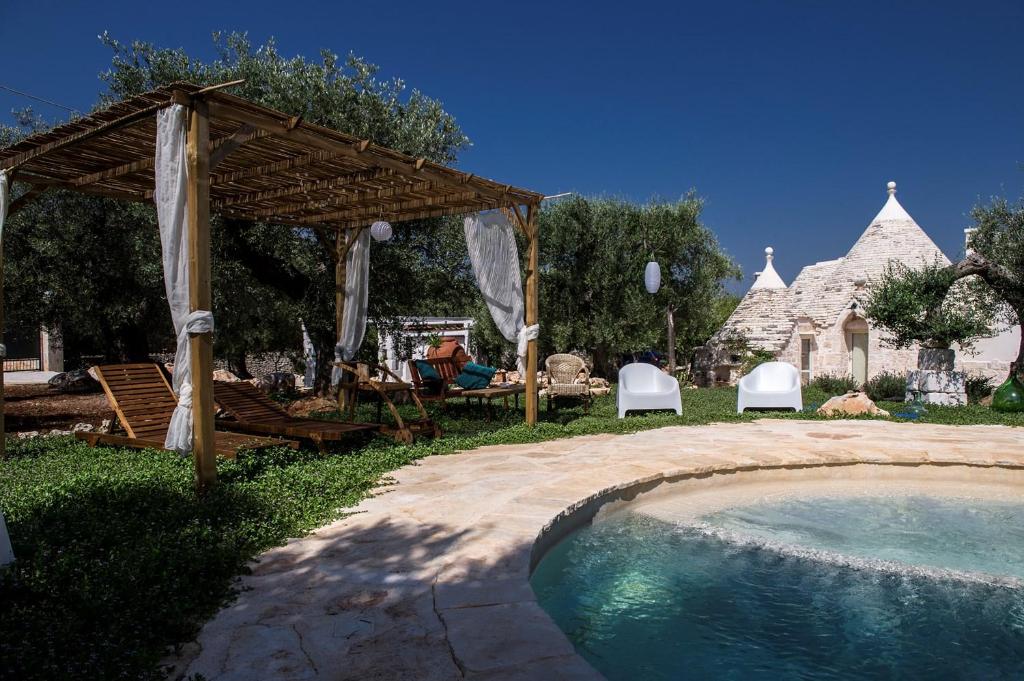 une cour avec une piscine, un pavillon, une table et des chaises dans l'établissement Dimora Trullivo, Charming House, à Castellana Grotte