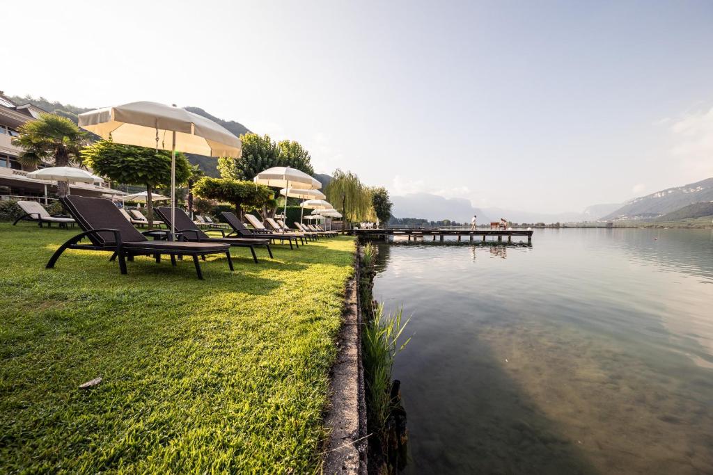 un groupe de chaises assises à côté d'une masse d'eau dans l'établissement Parc Hotel Am See, à Caldaro