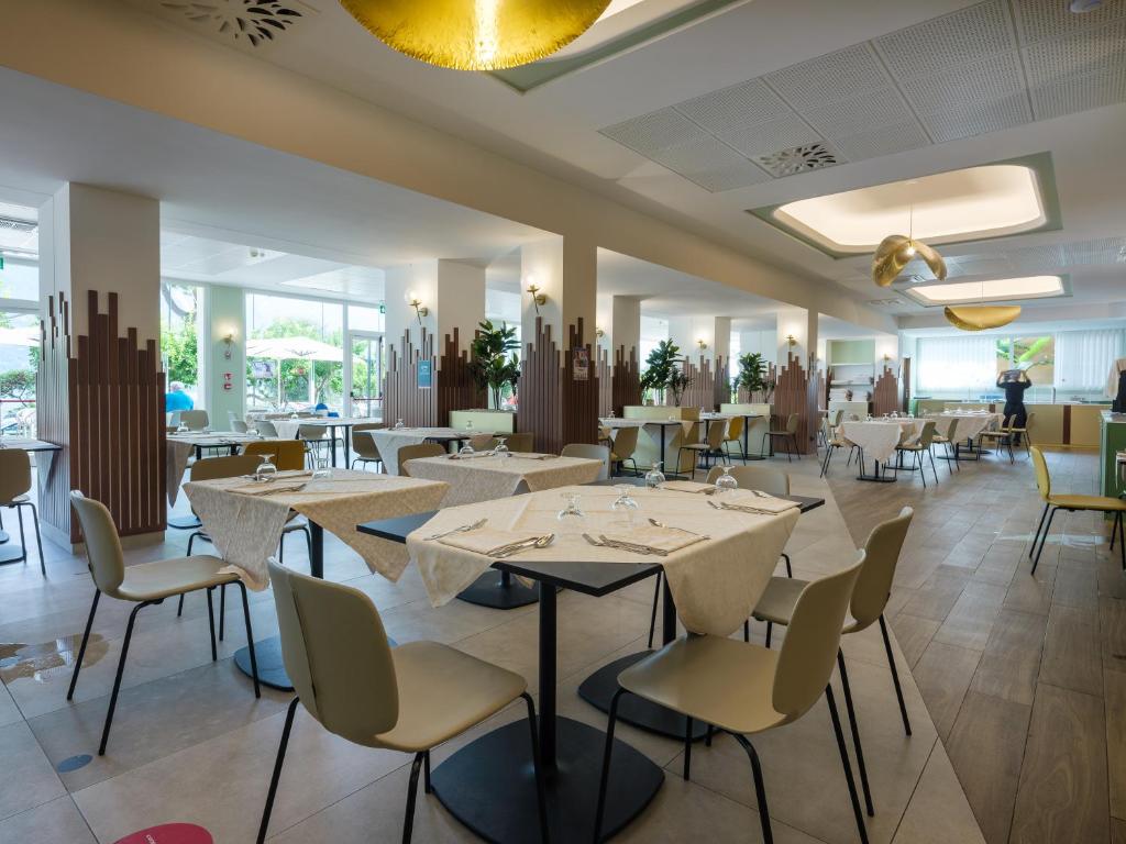 une salle à manger avec des tables et des chaises blanches dans l'établissement Hotel Leonardo Da Vinci, à Limone sul Garda