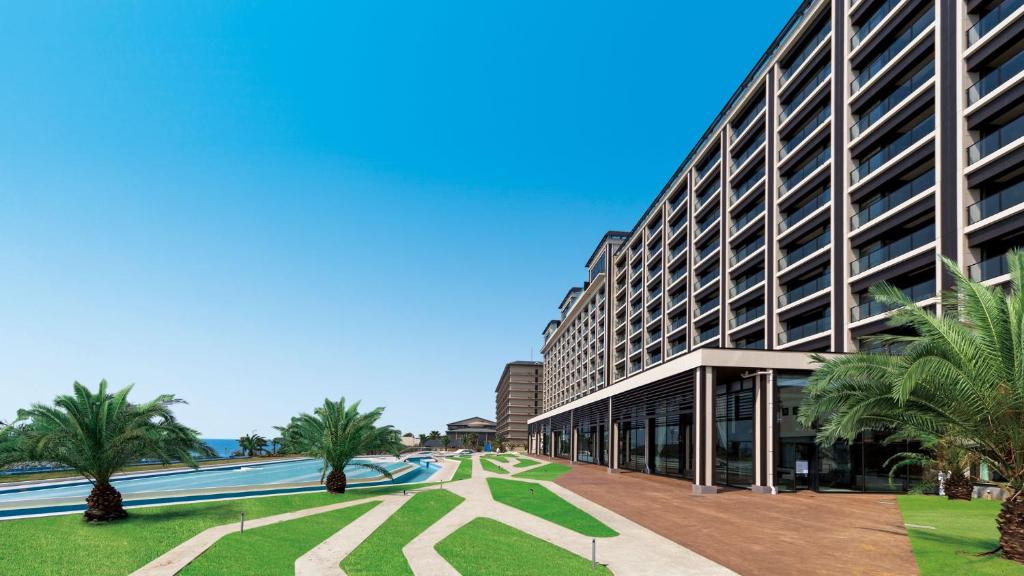 un grand bâtiment avec des palmiers devant dans l'établissement Ryugujo Spa Hotel Mikazuki Fujimitei, à Kisarazu