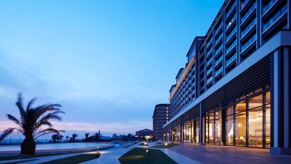un bâtiment avec un palmier devant dans l'établissement Ryugujo Spa Hotel Mikazuki Fujimitei, à Kisarazu
