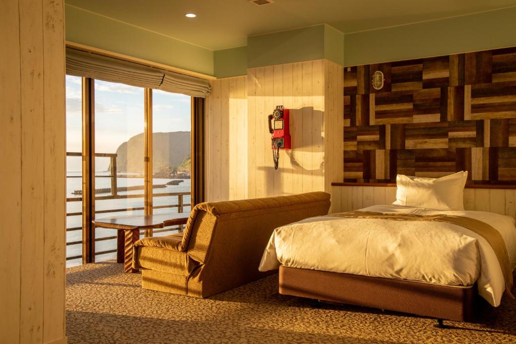 une chambre avec un lit, une chaise et une fenêtre dans l'établissement Meijikan, à Izu