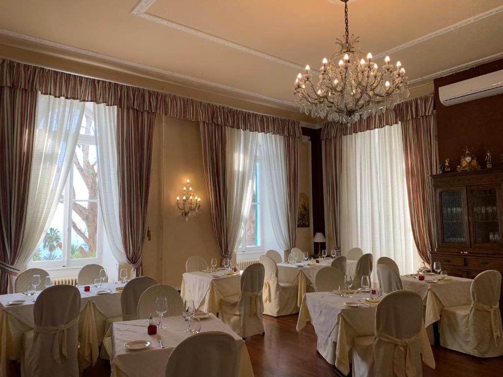 une salle à manger avec des tables et des chaises blanches et des fenêtres dans l'établissement Spa & Wellness by Des Anglais " Accesso SPA compreso", à Sanremo