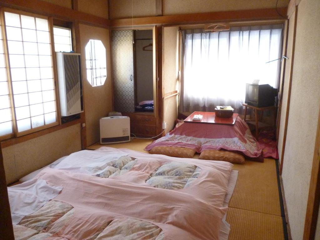 un grand lit dans une chambre avec une fenêtre dans l'établissement Uotoshi Ryokan, à Yamanouchi