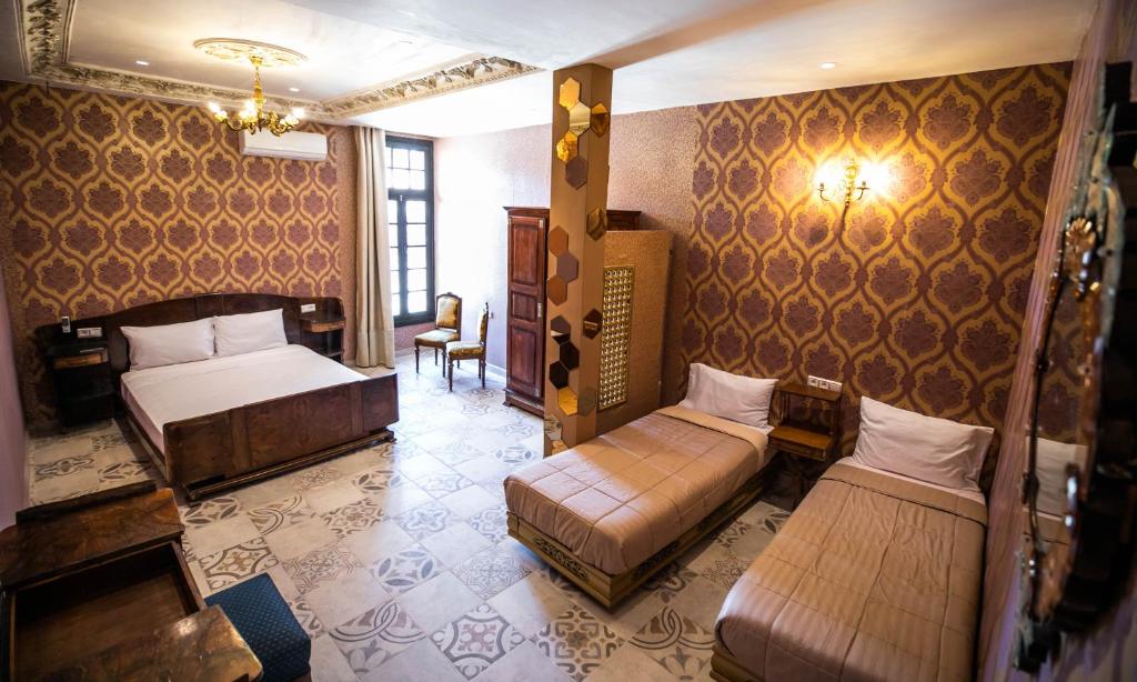 une chambre d'hôtel avec deux lits et une chaise dans l'établissement Palais Shazam & SPA, à Fès 37 autres photos