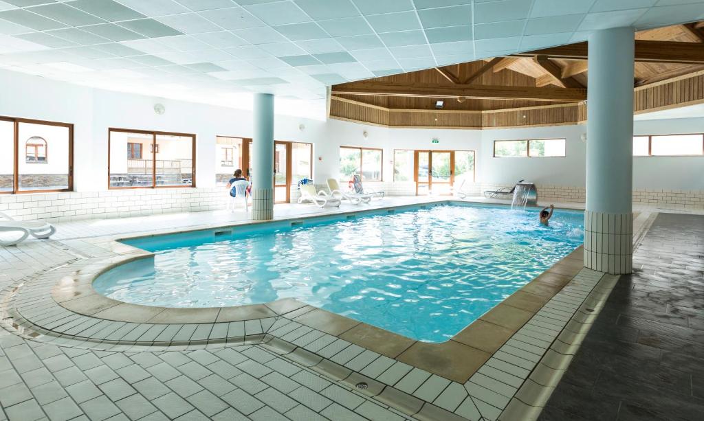 une grande piscine avec de l'eau bleue dans un immeuble dans l'établissement Résidence Odalys L'Orée des Pistes, à Saint-Sorlin-dʼArves 37 autres photos