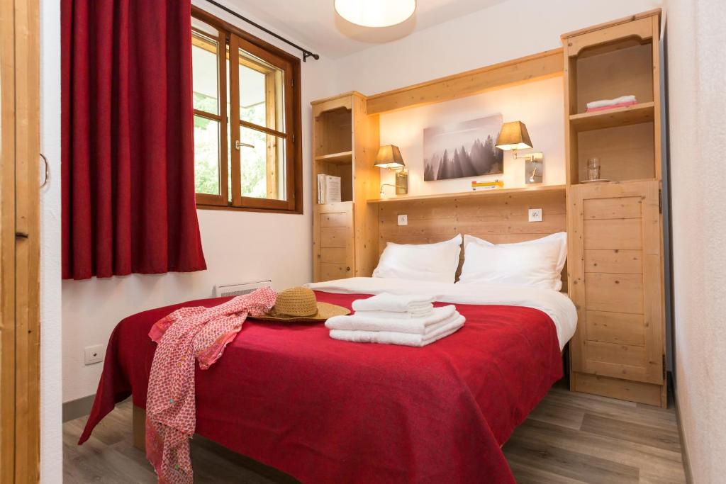 - une chambre avec un lit doté de draps rouges et de serviettes dans l'établissement Résidence Odalys L'Orée des Pistes, à Saint-Sorlin-dʼArves