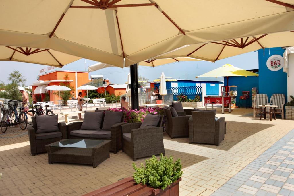 un patio avec des canapés et des chaises sous des parasols dans l'établissement Hotel Delle Nazioni, à Cesenatico