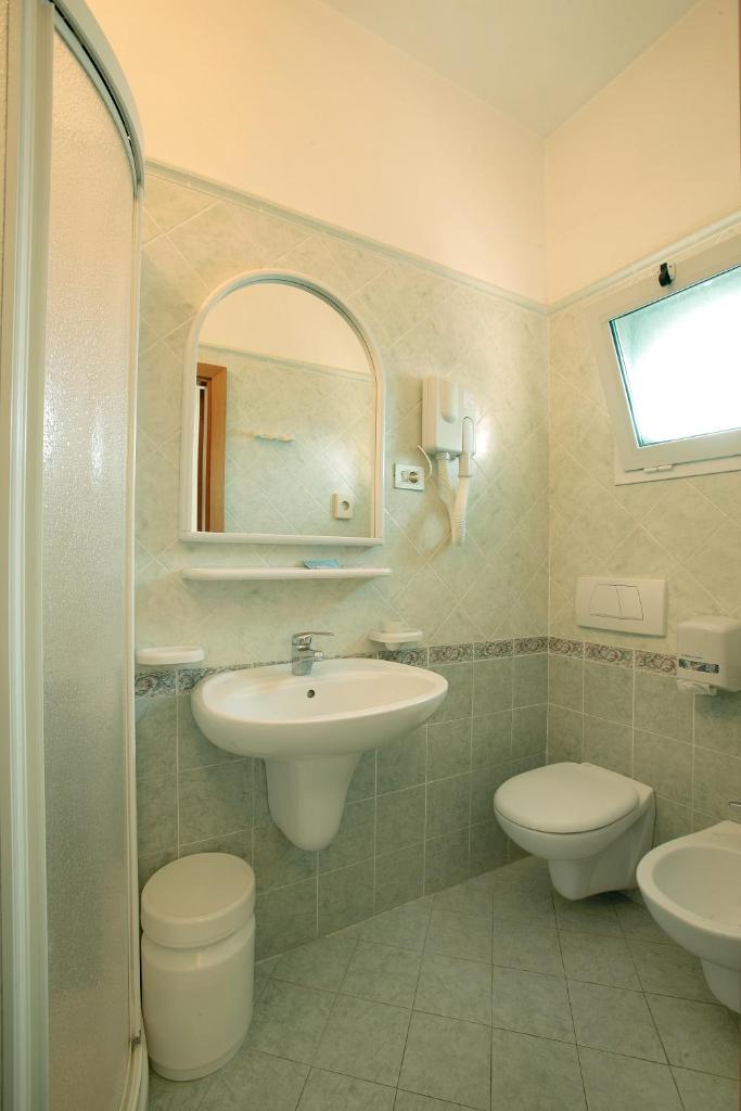une salle de bain avec un lavabo, des toilettes et un miroir dans l'établissement Hotel Delle Nazioni, à Cesenatico