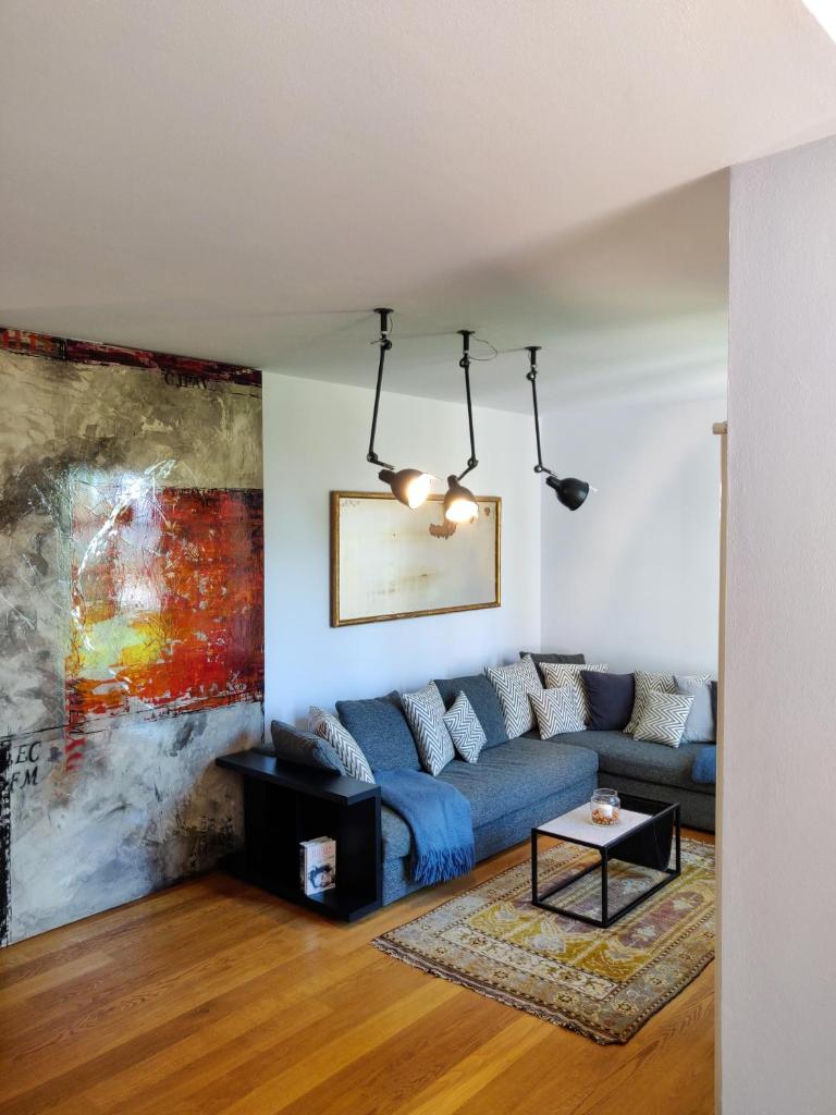 un salon avec un canapé bleu et un tableau dans l'établissement Scarpa Villas - Barolo Luxury Escape, à Verduno 90 autres photos