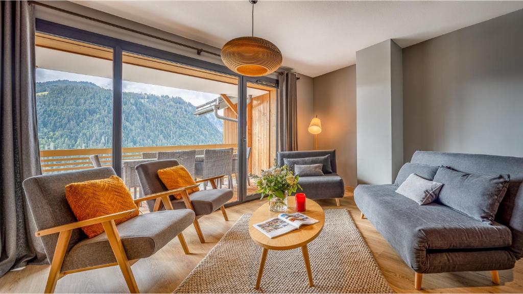un salon avec un canapé et des chaises et une grande fenêtre dans l'établissement Les 360 - Apt 2 - BO Immobilier - Châtel- Multipass Vacances été 2025 en option au tarif de 3euros par jour et par personne, à Châtel
