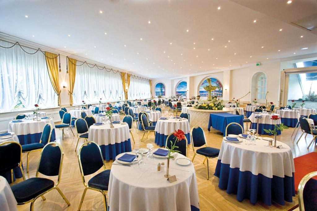 une salle de banquet avec des tables blanches et des chaises bleues dans l'établissement Sant Alphio Garden Hotel & SPA, à Giardini Naxos 123 autres photos