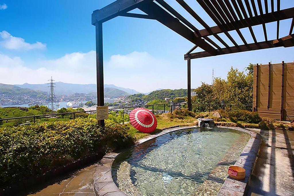 - une piscine dans une arrière-cour avec un toit dans l'établissement Ooedo Onsen Monogatari Nagasaki Hotel Seifu, à Nagasaki