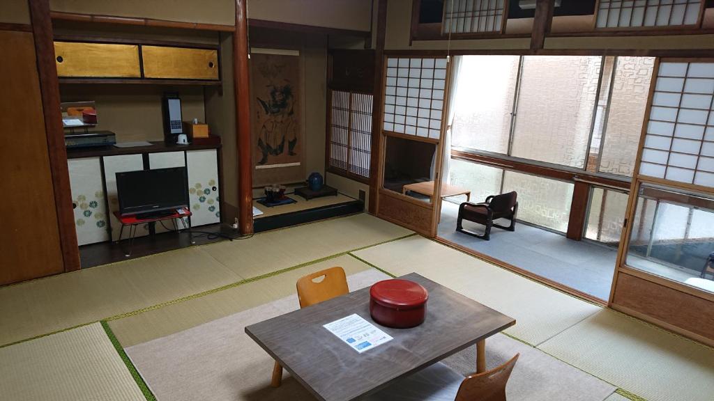 un salon avec une table, des chaises et des fenêtres dans l'établissement Wajimaya Ryokan, à Kyoto