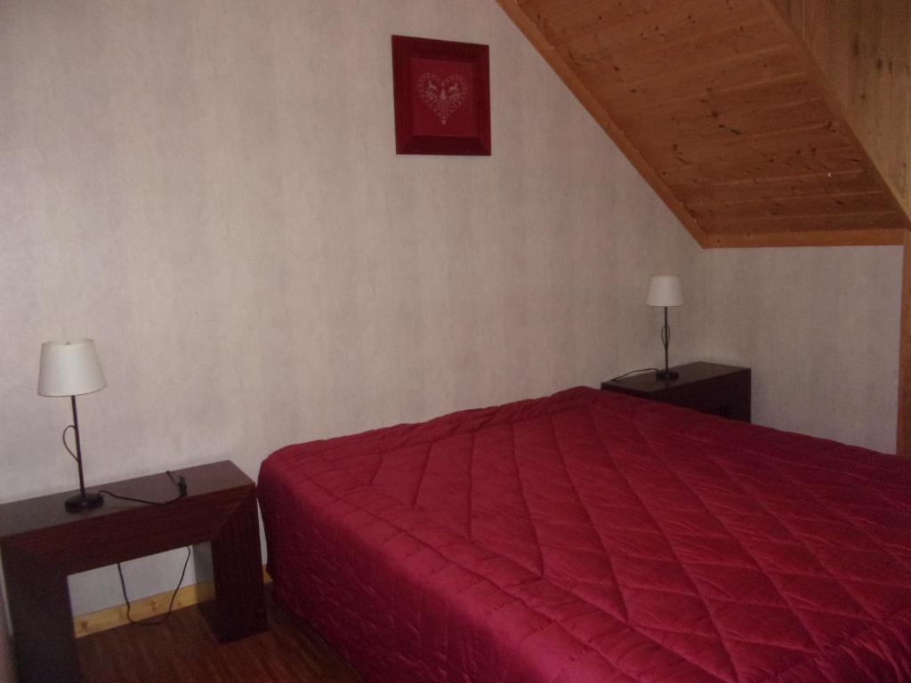 une chambre avec un lit rouge et deux tables de nuit dans l'établissement chez Angèle, à Le Mont-Dore