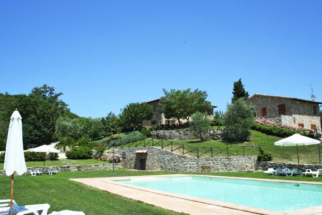 une piscine avec une maison en arrière-plan dans l'établissement Villa Orizzonte - Homelike Villas, à Todi