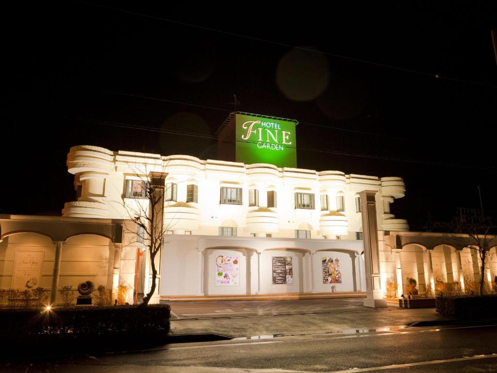 un bâtiment blanc avec un panneau vert au sommet dans l'établissement Hotel Fine Garden Suzuka, à Suzuka