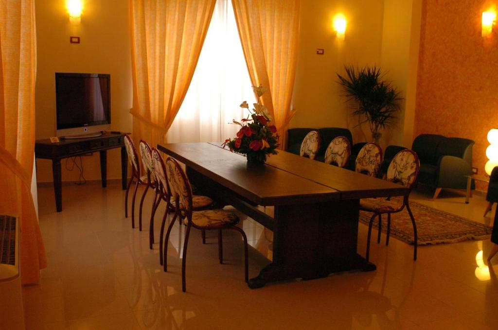 une pièce avec une table, des chaises et une télévision dans l'établissement Sait Hotel & BB, à Terme Vigliatore