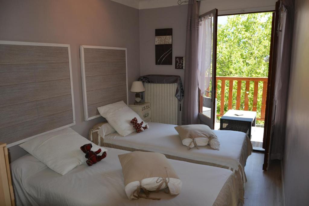 deux lits dans une chambre avec balcon dans l'établissement Hotel & Restaurant Le Chalvet, à Embrun