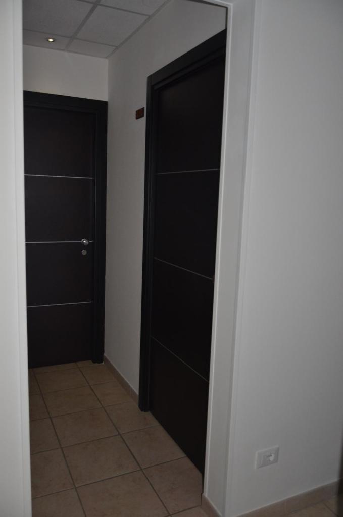 - un couloir avec deux portes noires et du carrelage dans l'établissement Residence Della Vista, à Rimini 28 autres photos