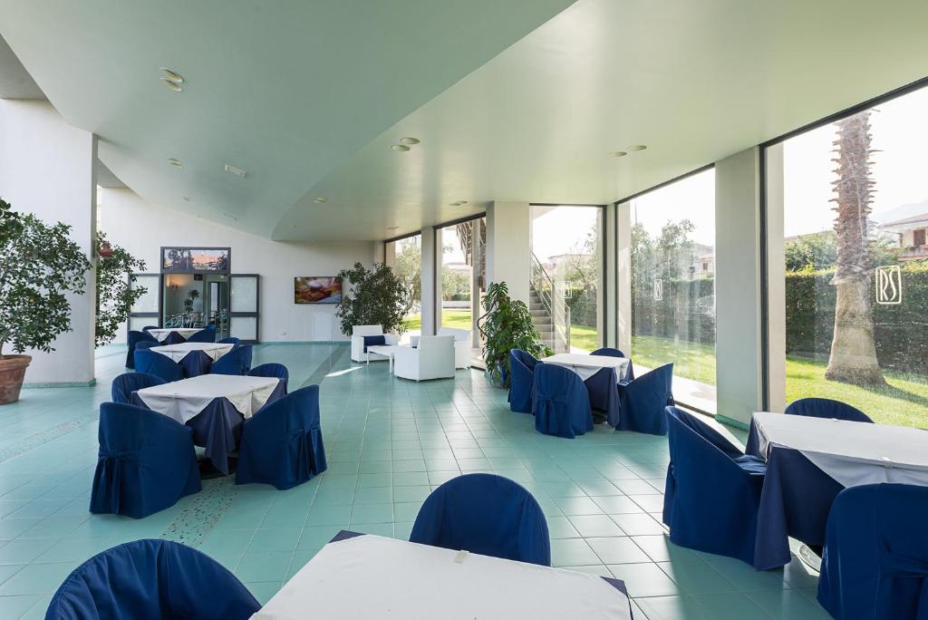 un restaurant avec des chaises, des tables et des fenêtres bleues dans l'établissement Rada Siri, à Montepaone