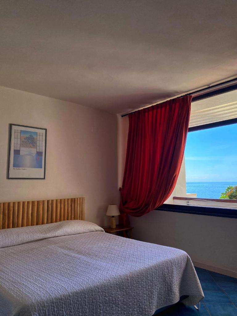 une chambre avec un lit et une fenêtre avec l'océan dans l'établissement Puntaquattroventi, à Ercolano