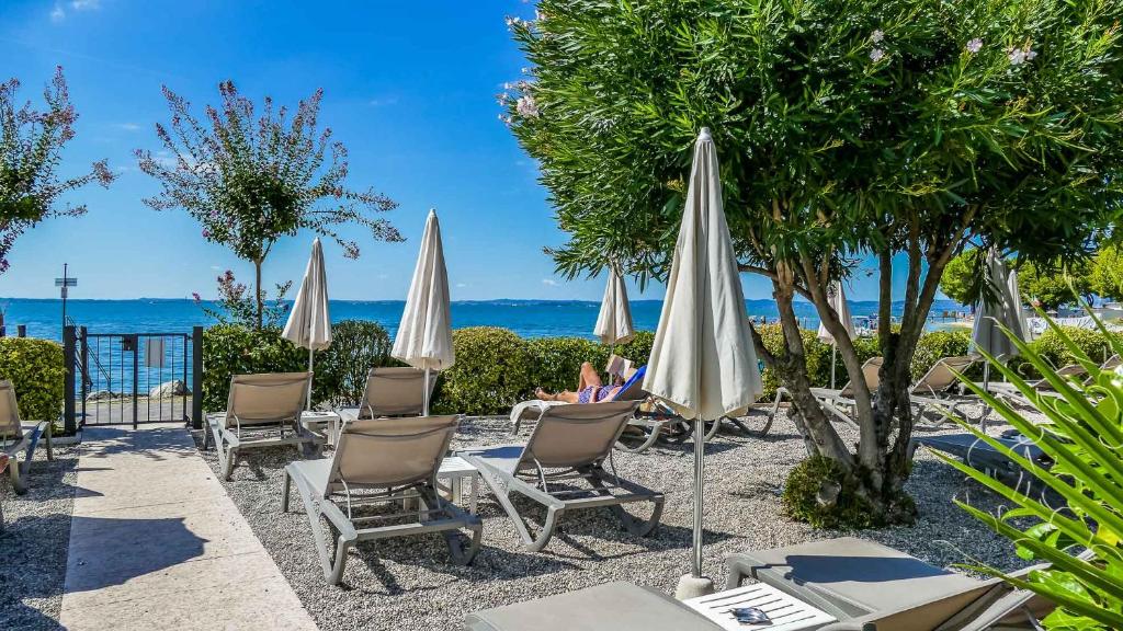 une terrasse avec des chaises et des parasols et l'océan dans l'établissement Hotel Villa Letizia, à Bardolino