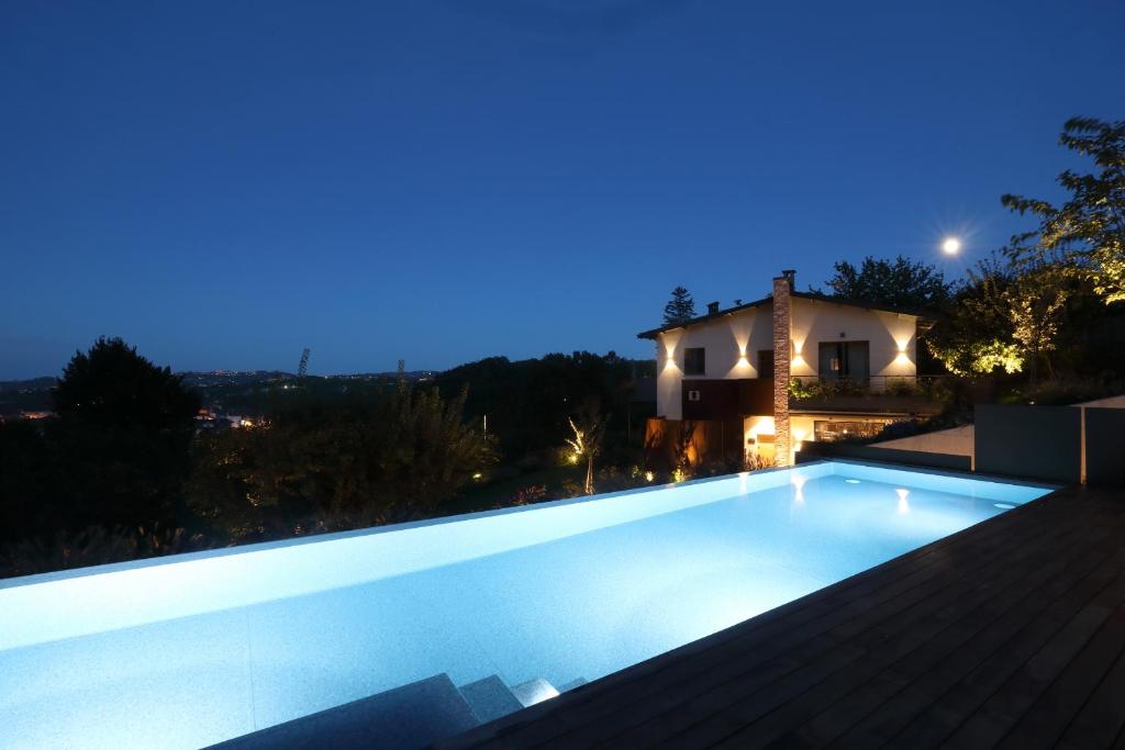 - une piscine la nuit avec une maison en arrière-plan dans l'établissement Villa Carla @ Barolo, à Barolo
