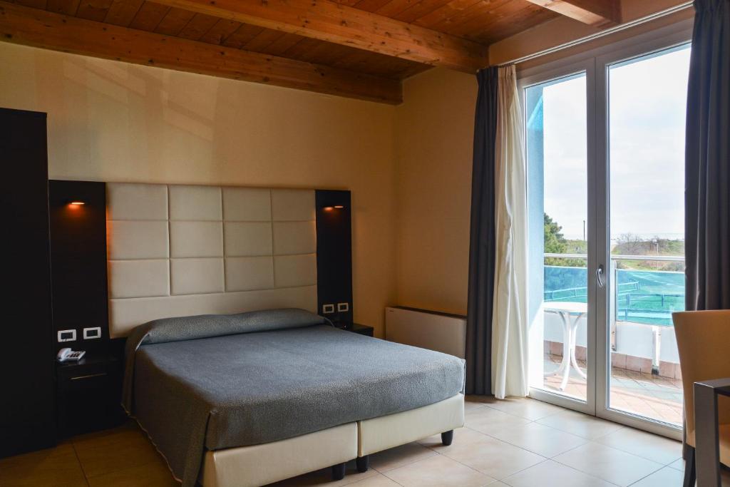 une chambre avec un lit et une grande fenêtre dans l'établissement Hotel-Residence- Le Dune Breakfast & private beach included, à Lido Adriano