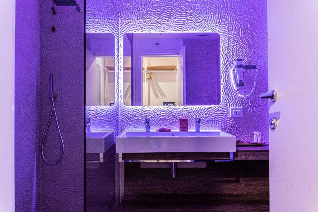 une salle de bains pourpre avec deux lavabos et un miroir dans l'établissement Suite du Parc & Hotel, à Giulianova