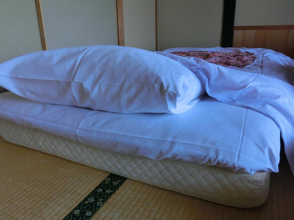 - un lit non aménagé avec une couverture bleue dans l'établissement Tajimaya, à Nakatsugawa