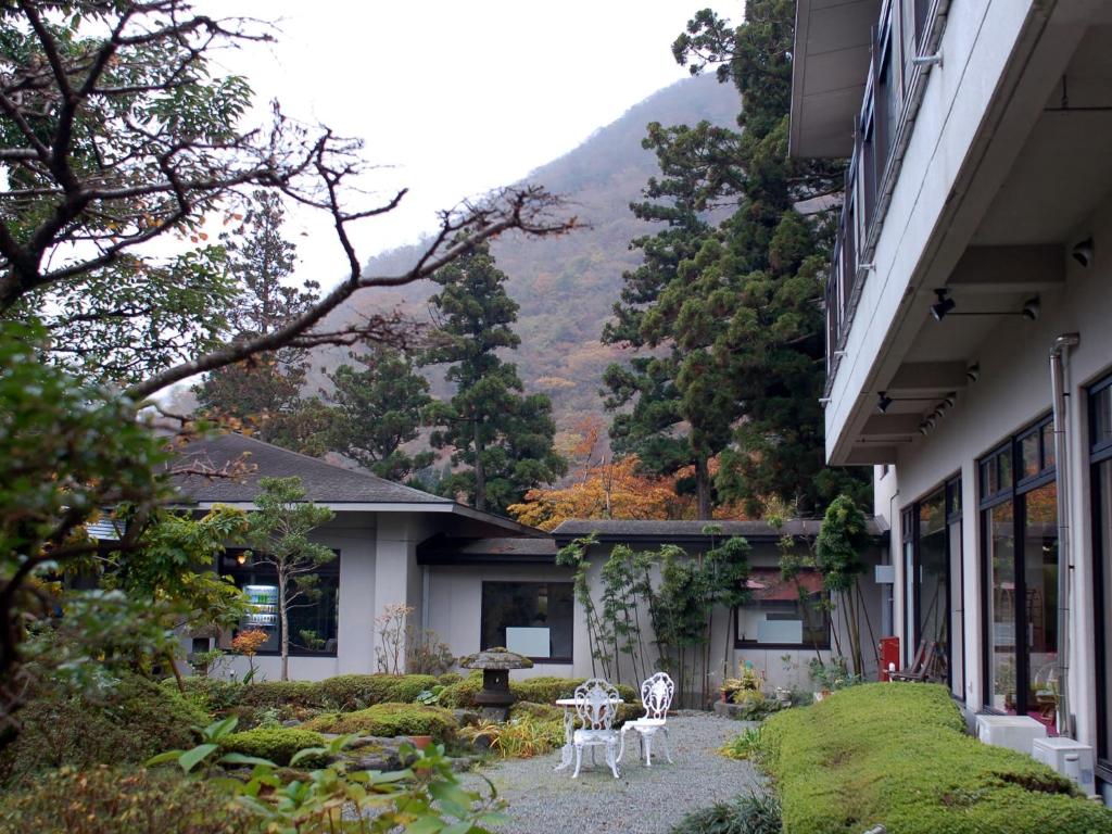une maison avec deux chaises et une table dans une cour dans l'établissement Kinokuniya Ryokan, à Hakone