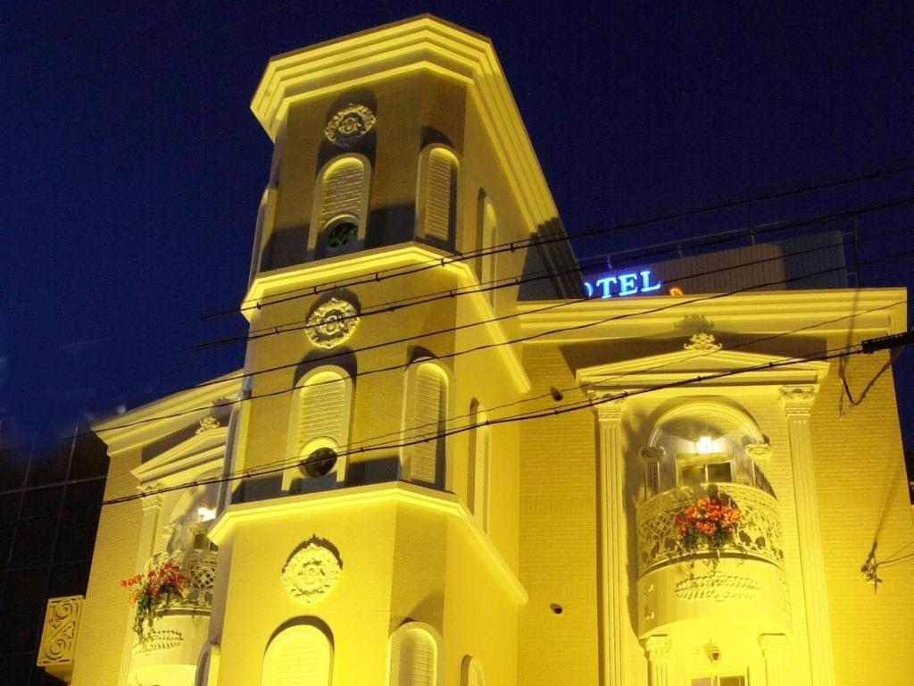 un grand bâtiment jaune avec une tour d'horloge la nuit dans l'établissement Hotel Fine Sakai, à Sakai