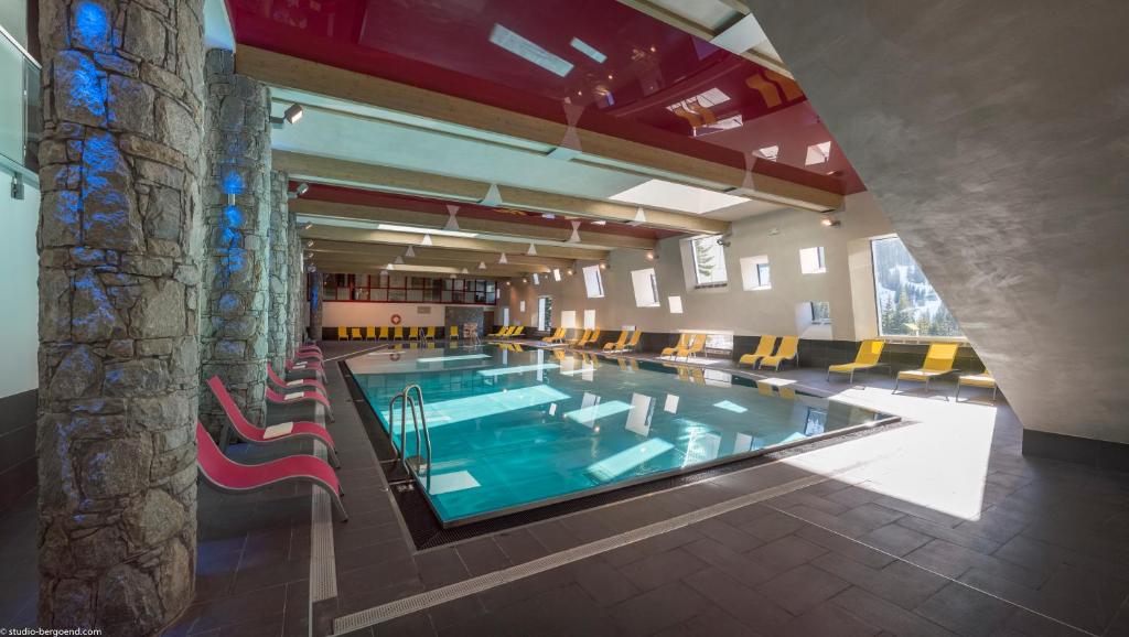 - une grande piscine dans un bâtiment avec des chaises dans l'établissement CGH Résidence Boutique Le Centaure, à Flaine