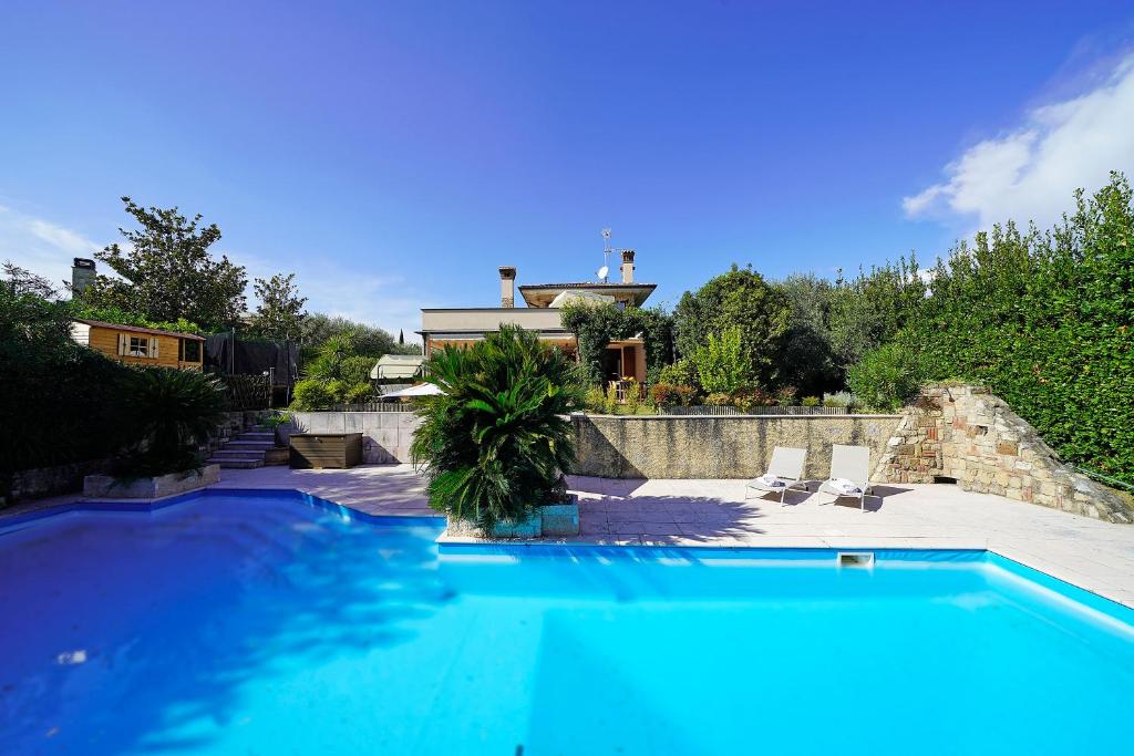 une grande piscine bleue devant une maison dans l'établissement Villa Riai, à Moniga del Garda