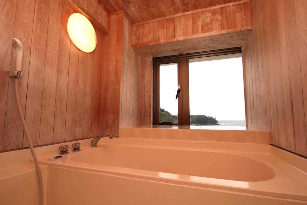 une baignoire dans une pièce avec une fenêtre dans l'établissement Ooedo Onsen Monogatari Toi Marine Hotel, à Izu