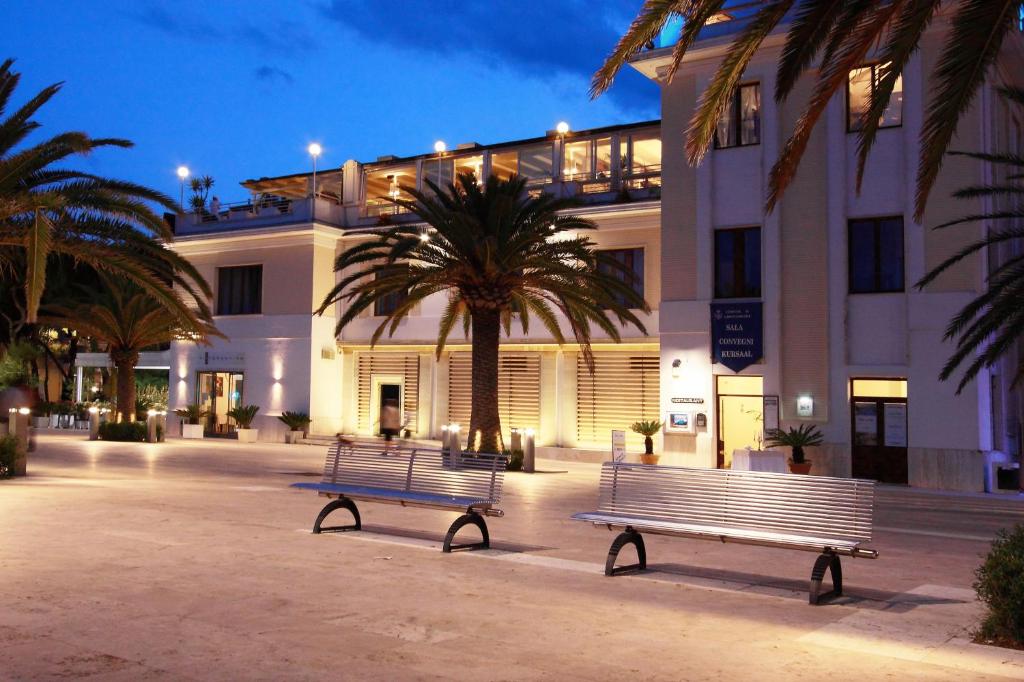 deux bancs devant un bâtiment avec un palmier dans l'établissement Eurotel, à Grottammare