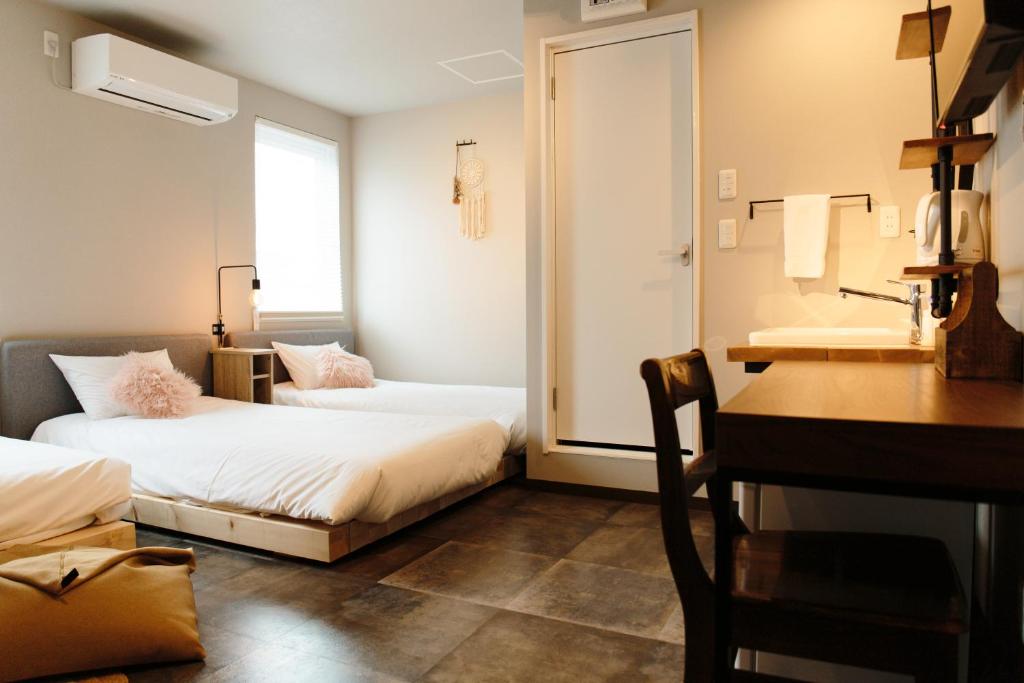 Cette chambre comprend 2 lits, un bureau et un lavabo. dans l'établissement Lampstand STAY Asahikawa, à Asahikawa